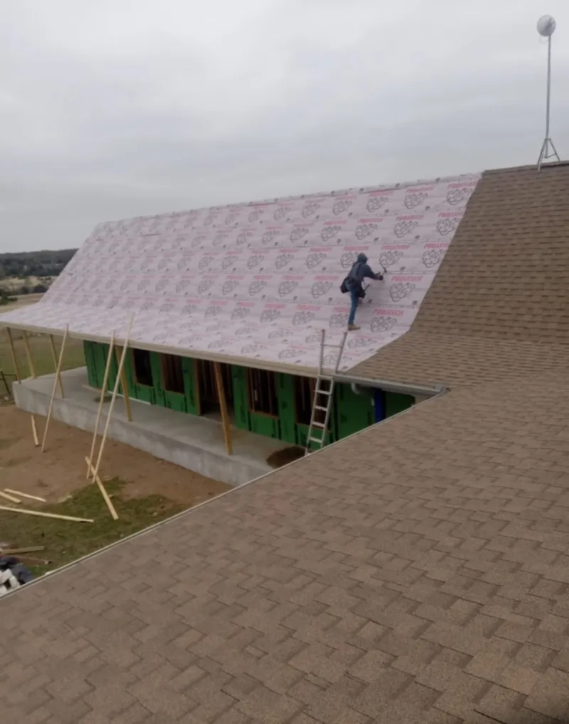 Worker preparing underlayment for a metal roof installation in Port Clinton
